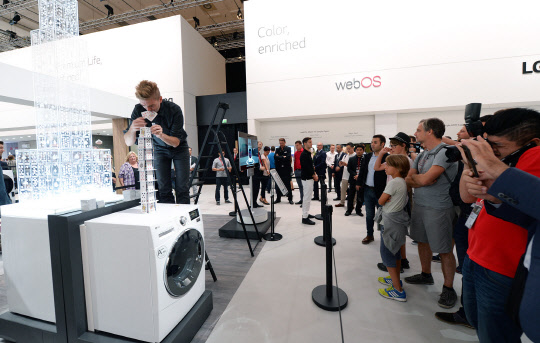 5일(현지시간) 독일 베를린에서 열리고 있는 유럽 최대 가전전시회 IFA 2016에서 관람객들이 동작 중인 드럼세탁기 위에서 카드탑을 쌓고 있는 브라이언 버그를 지켜보고 있다. <LG전자 제공>